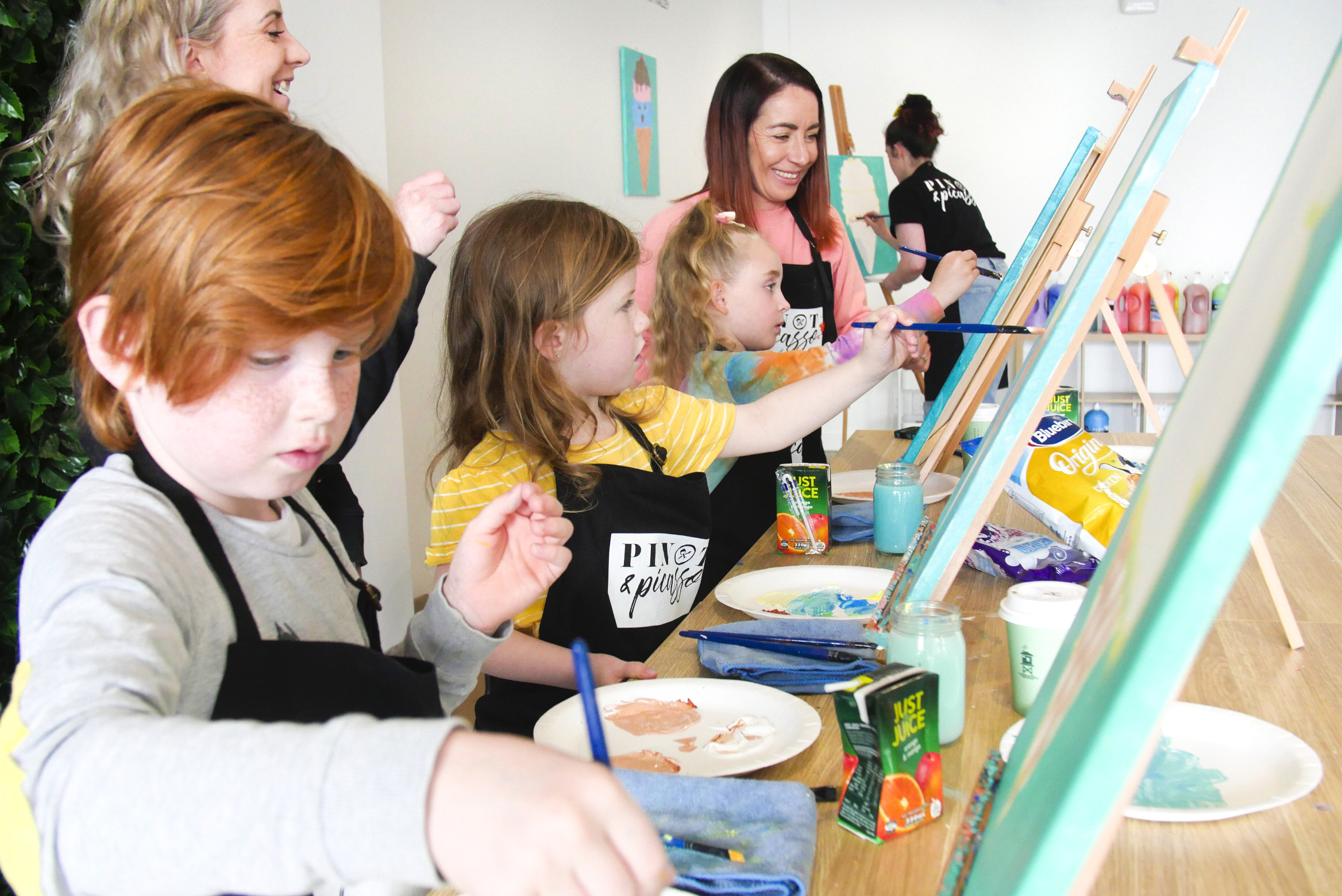 Young children painting with adults helping